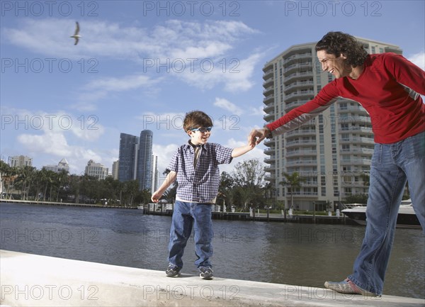 Hispanic father holding son's hand