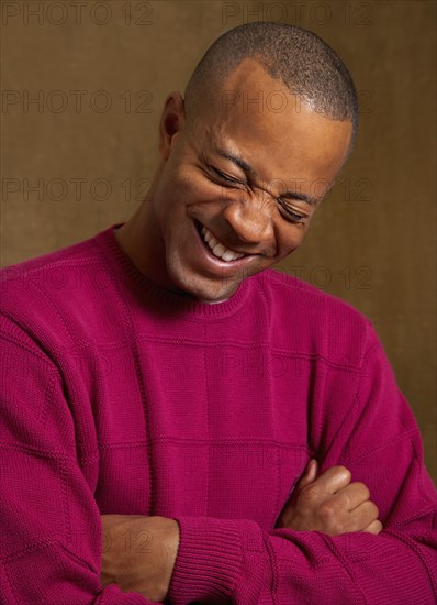 African man laughing with arms crossed