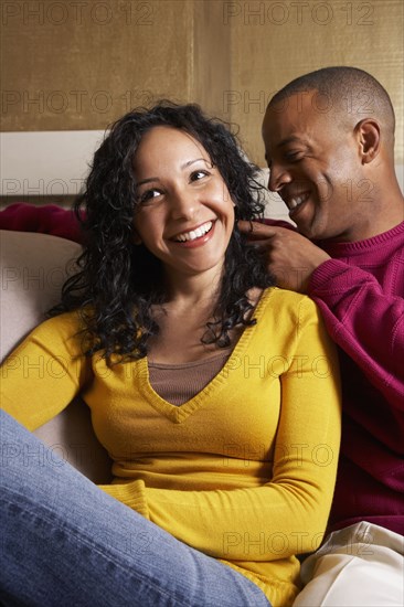 Multi-ethnic couple hugging on sofa