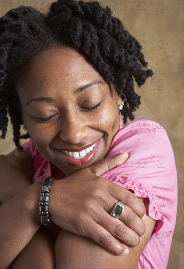 African woman hugging self