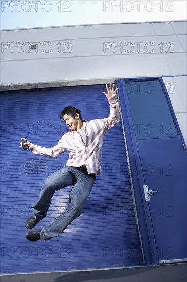 Pacific Islander man listening to mp3 player and jumping