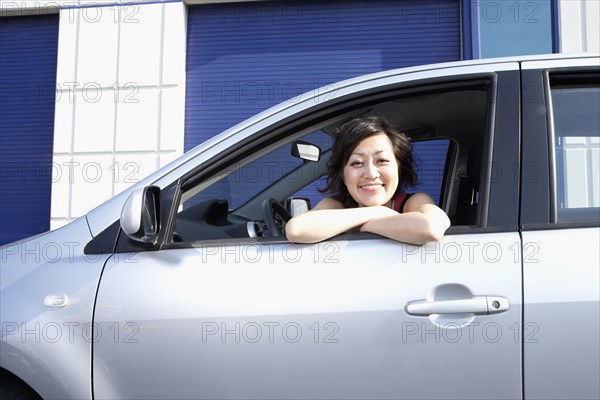 Portrait of Asian woman leaning out car window