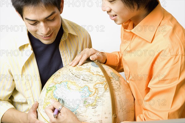 Two young men looking at globe
