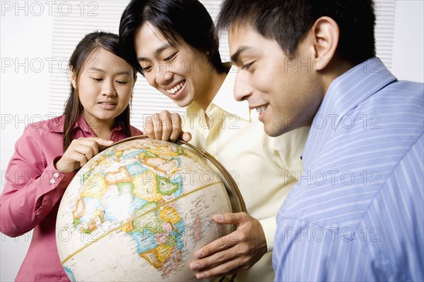 Three friends looking at globe