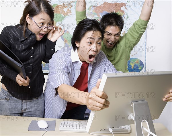 Young businesspeople cheering and looking at computer