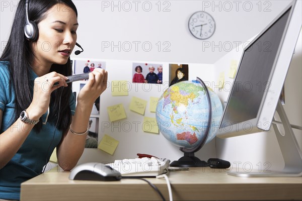 Asian businesswoman filing fingernails at desk