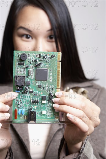 Asian businesswoman holding up computer circuit board