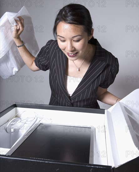 Asian businesswoman opening box with new computer