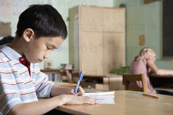 Asian boy writing in classroom