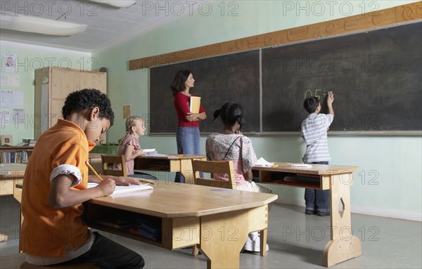 Asian boy writing on blackboard