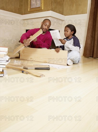 African father and son putting furniture together