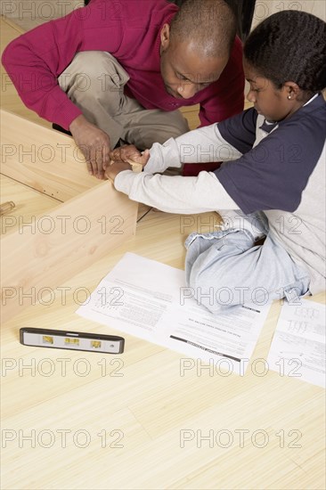 African father and son putting furniture together
