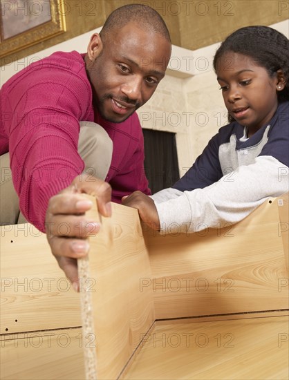 African father and son putting furniture together