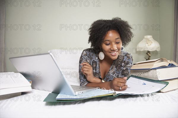 African woman studying on bed