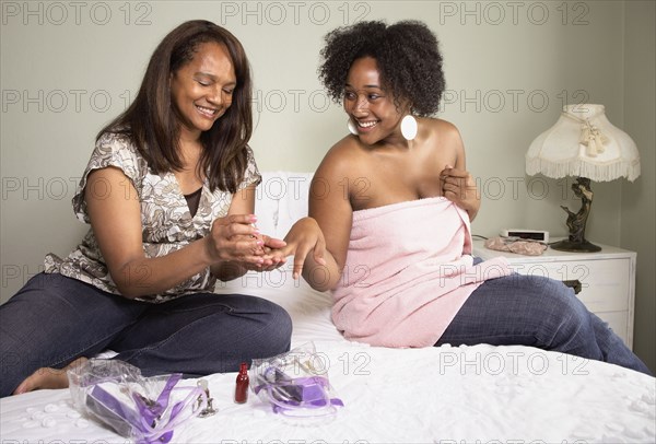 African American mother painting daughter's fingernails