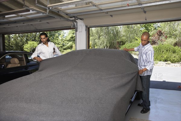 Multi-ethnic men covering car