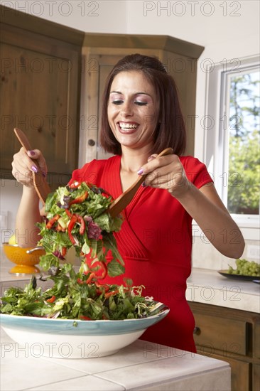 Hispanic woman tossing salad