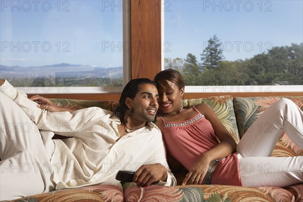 Multi-ethnic couple sitting on sofa