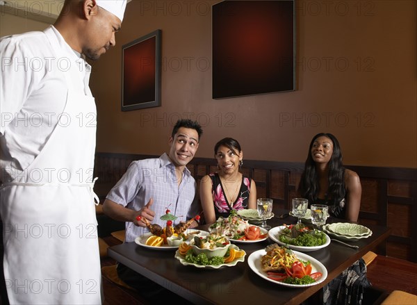 Multi-ethnic friends complimenting chef