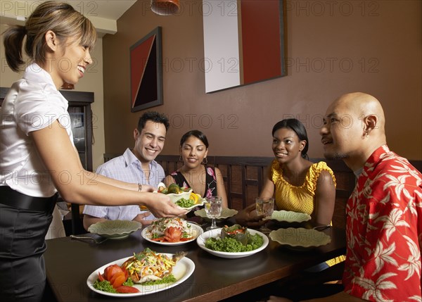 Asian female server bringing food to table