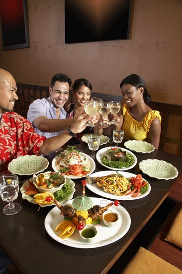 Multi-ethnic friends toasting at restaurant