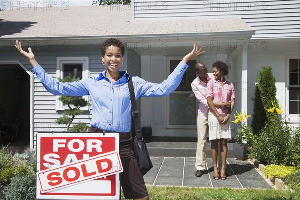 African American real estate agent and couple in front of new house