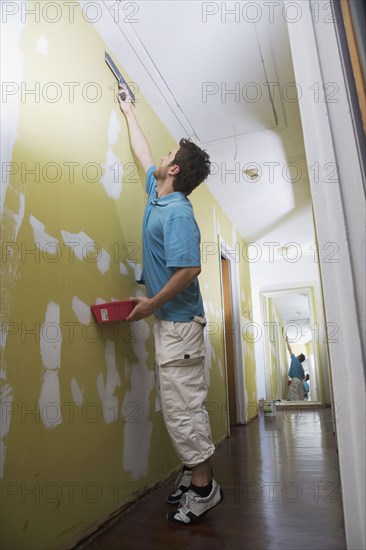 Middle Eastern man spackling wall