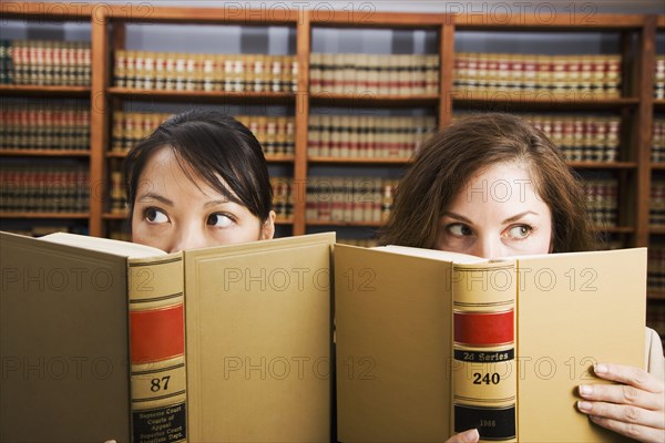 Multi-ethnic women holding library reference book