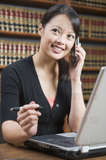 Asian woman talking on cell phone in library