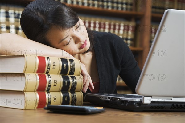 Asian woman sleeping on stack of library books