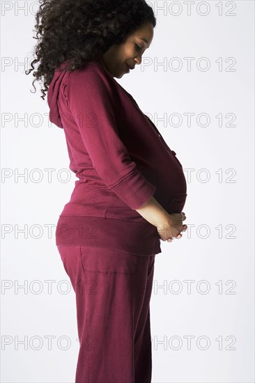 Pregnant Mixed Race woman looking at belly