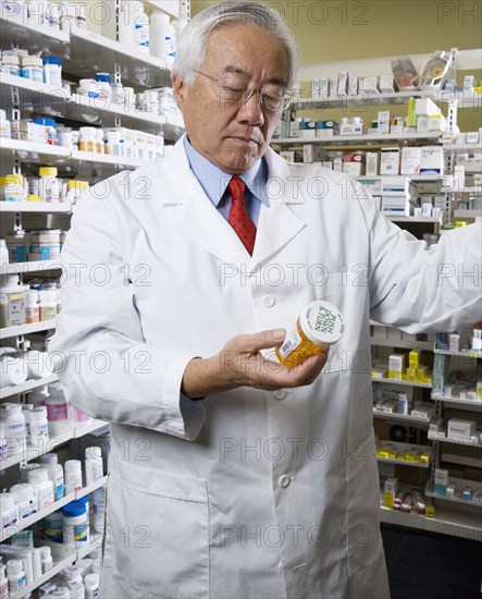 Senior Asian pharmacist reading medication