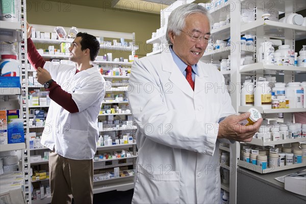 Senior Asian pharmacist reading medication