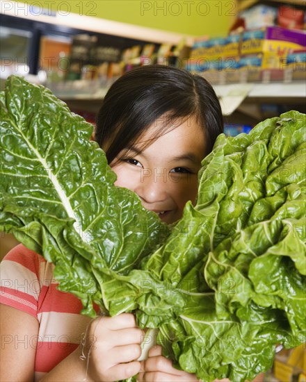 Asian girl holding green leaf vegetables