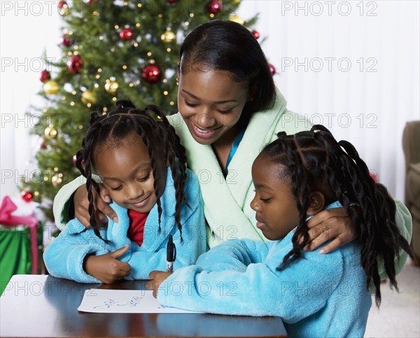 African mother and daughters writing letter to Santa Claus