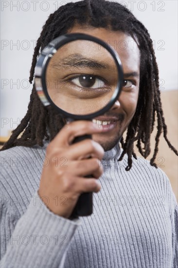 African man looking through magnifying glass