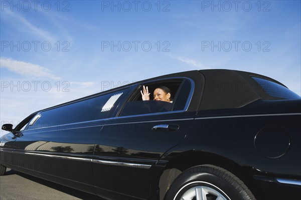 African businesswoman waving from limousine