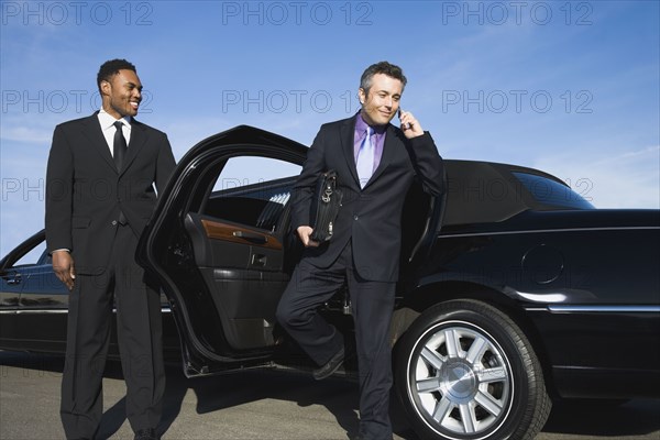 Hispanic businessman getting out of limousine