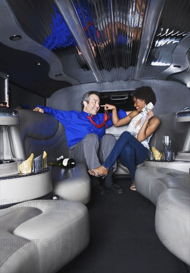 Multi-ethnic couple in with champagne and money in limousine