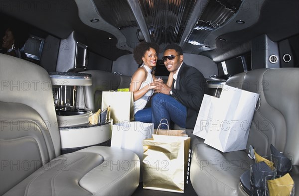 African couple with shopping bags in limousine