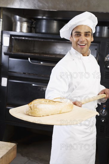 Hispanic male baker holding fresh bread