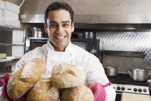 Hispanic male baker holding fresh bread