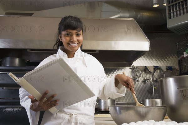 Mixed Race female baker mixing batter