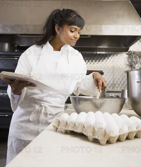 Mixed Race female baker mixing batter