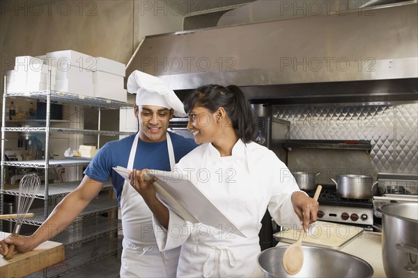 Multi-ethnic chefs looking at cookbook