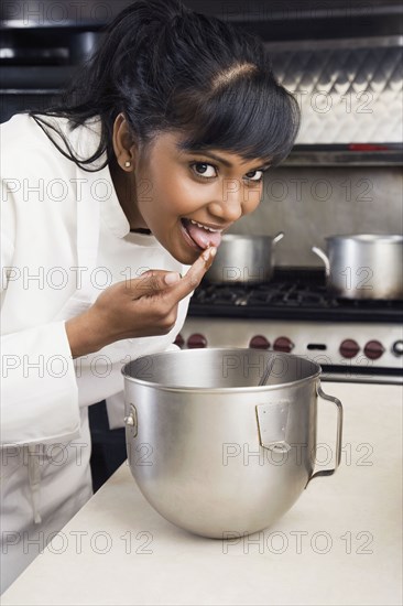 Mixed Race female pastry chef tasting batter