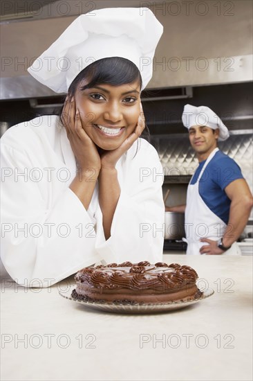 Mixed Race female pastry chef with cake