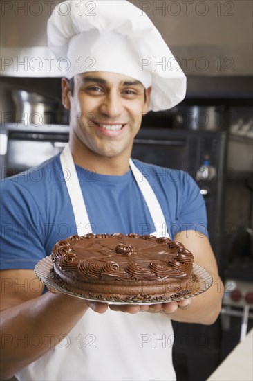 Hispanic male pastry chef holding cake