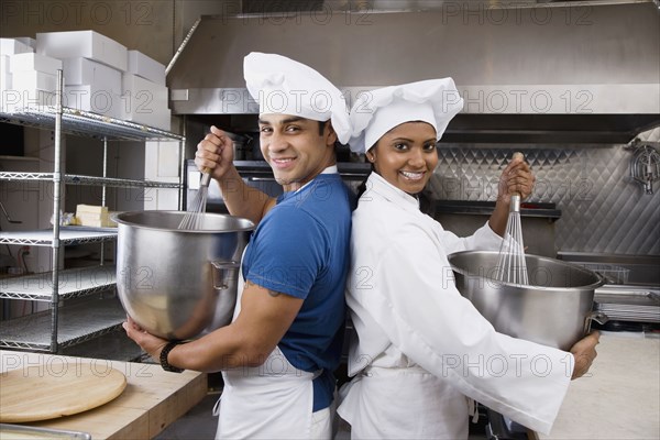 Multi-ethnic pastry chefs mixing batter back to back