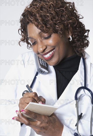 Mixed race doctor talking on cell phone and taking notes